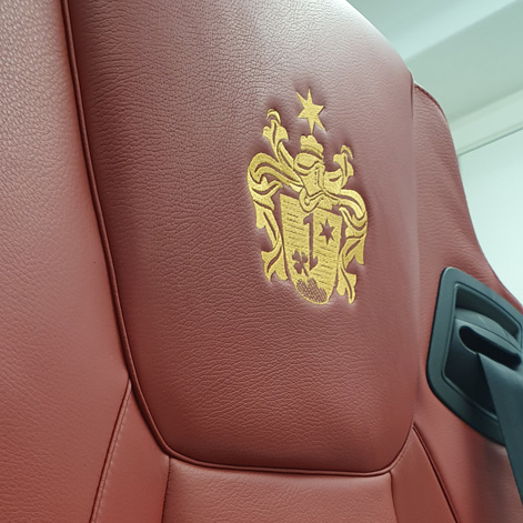 Autositz mit Familienwappen als Stickerei auf der Nackenst�tze.
